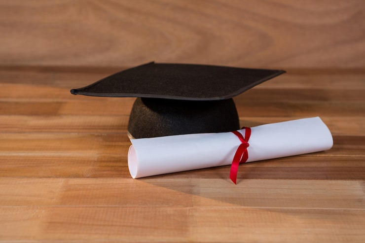 Foto gratuito primo piano del certificato di laurea con malta bordo su un tavolo