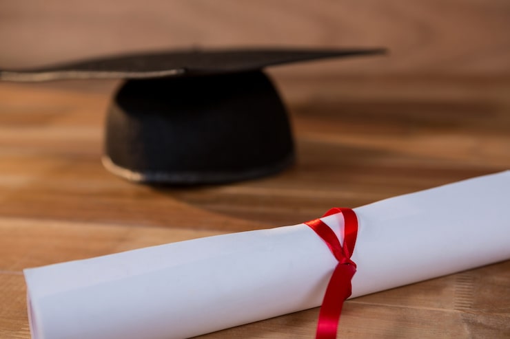 Foto gratuito primo piano del certificato di laurea con malta bordo su un tavolo