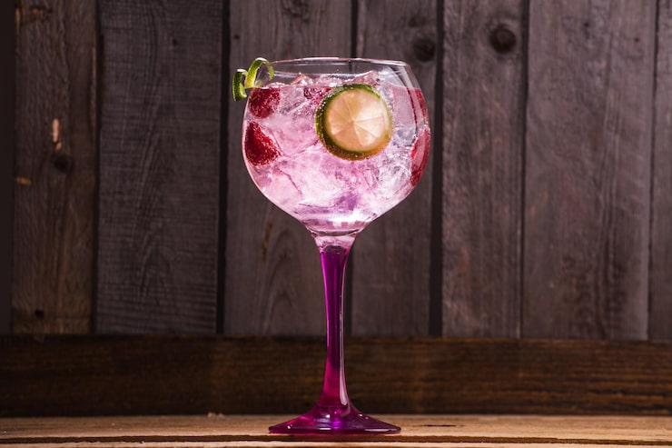 Foto gratuito primo piano di gin tonic con ghiaccio e lamponi su uno sfondo di legno