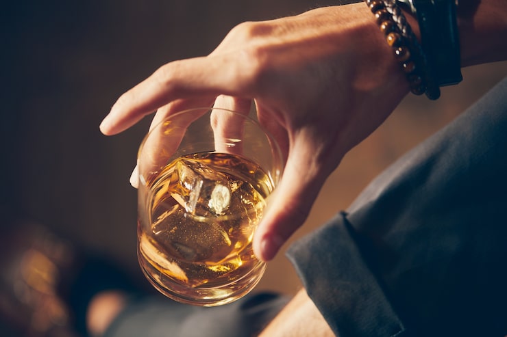 Foto gratuito scatto da vicino ad alto angolo di un maschio che tiene un bicchiere di whisky