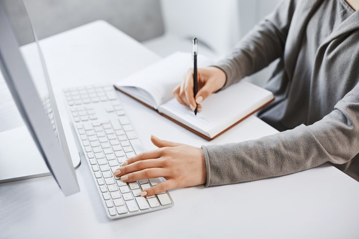 Foto gratuito sono in grado di gestire più attività. ragazza potata del colpo potata che scrive sulla tastiera e che fa le note mentre esaminando lo schermo di computer e studiando il nuovo grafico commerciale. non c'è tempo per riposare