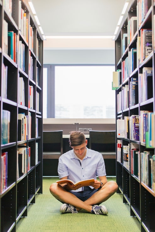 Foto gratuito srudent con libro seduto sul pavimento