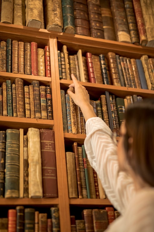 Foto gratuito studente intelligente che cerca un libro in biblioteca