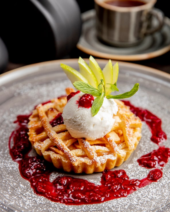 Foto gratuito torta servita con fette di mela gelato e salsa ai frutti di bosco
