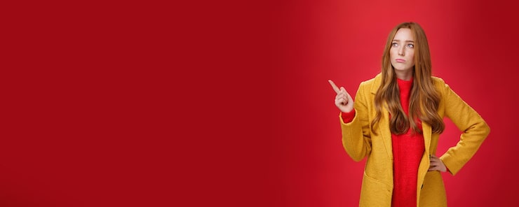Foto gratuito triste e cupa carina ragazza zenzero in s che indossa un cappotto giallo alla moda che tiene la mano sulla vita che fa il broncio