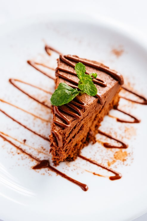 Foto gratuito un pezzo di torta al cioccolato con menta e cioccolatina sotto le luci con uno sfondo sfocato