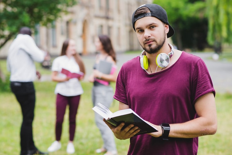 Foto gratuito uomo di barba che tiene libro di testo in piedi