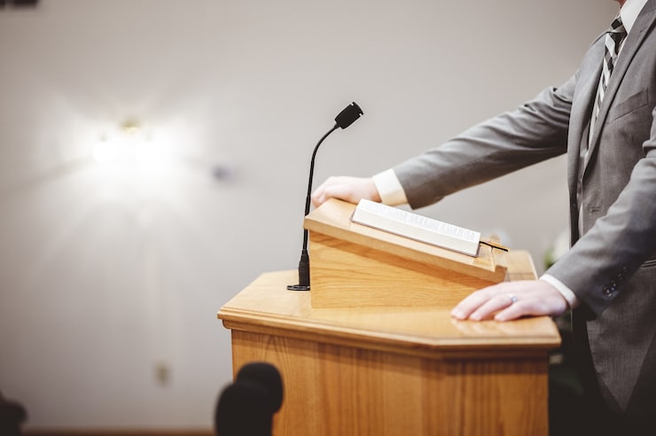 Foto gratuito uomo in abito formale che predica la sacra bibbia dalla tribuna all'altare della chiesa