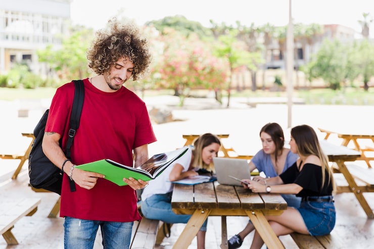 Foto gratuito uomo sorridente che legge libro di testo vicino agli amici