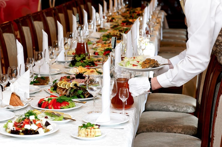 Foto cameriere che serve cibo al tavolo di lusso apparecchiato al ricevimento di nozze catering nel ristorante