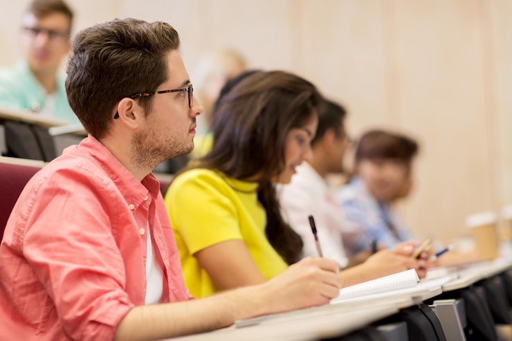 Foto concetto di istruzione, scuola superiore, università, apprendimento e persone - gruppo di studenti internazionali con quaderni che scrivono in sala conferenze e parlano