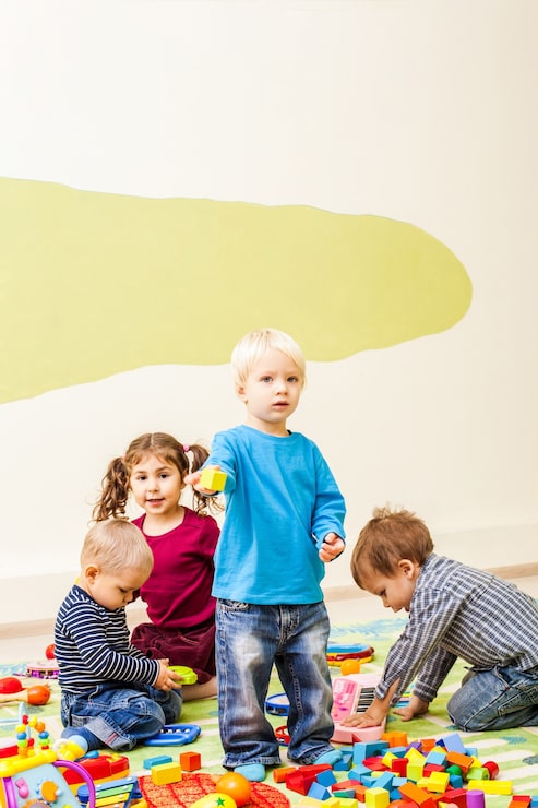 Foto i bambini carini giocano all'asilo. un ragazzino è interessato al giocattolo del suo amico