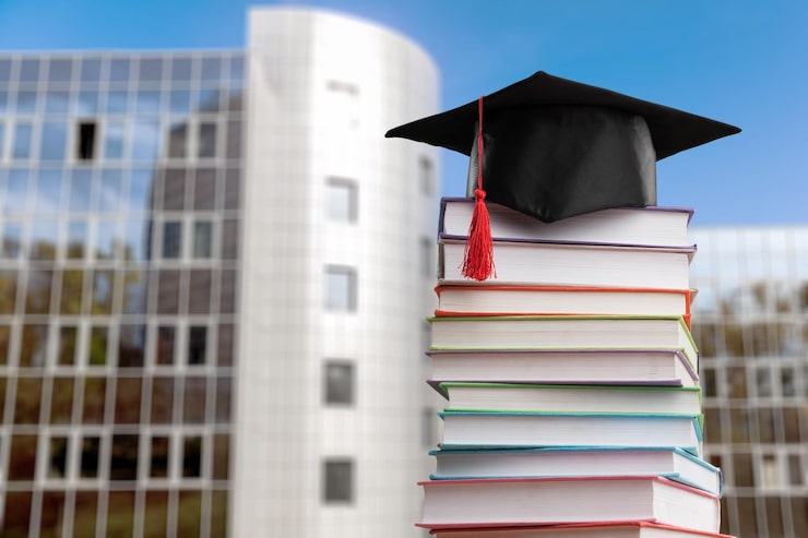 Foto impila i libri di scuola con il cappello di laurea nero