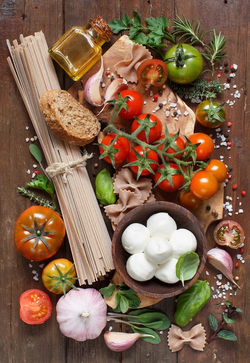 Foto ingredienti di cucina italiana mozzarella, pasta, pomodori, aglio, erbe aromatiche, olio d'oliva e altro