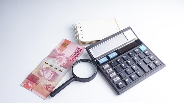 Photo kalkulator hitam uang kertas rupiah indonesia kaca pembesar dan buku catatan