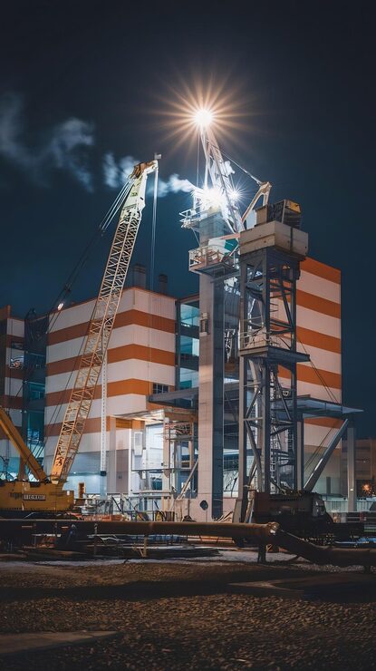 Photo latar belakang untuk lokasi konstruksi bangunan gaya industri dengan crane dan suar cahaya di malam hari