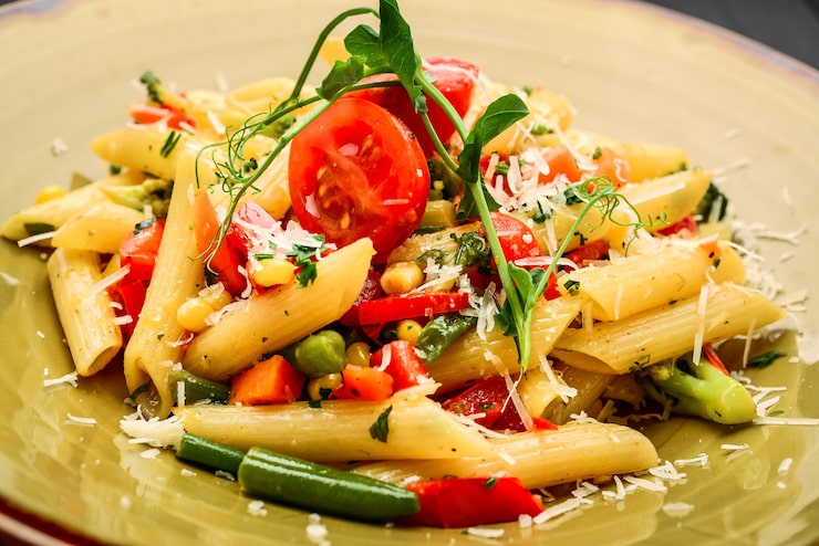 Foto pasta di penne al pomodoro e pancetta su un tavolo di legno nero