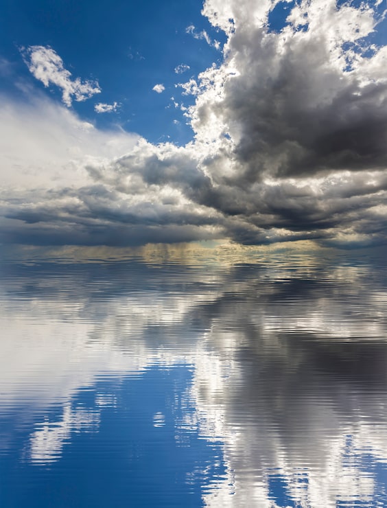 Photo pemandangan fantastis awan putih dan gelap cerah yang diterangi matahari dengan latar belakang langit biru tua yang memantul di air. keindahan dan kekuatan alam, masalah lingkungan, ekologi, dan konsep perubahan iklim.