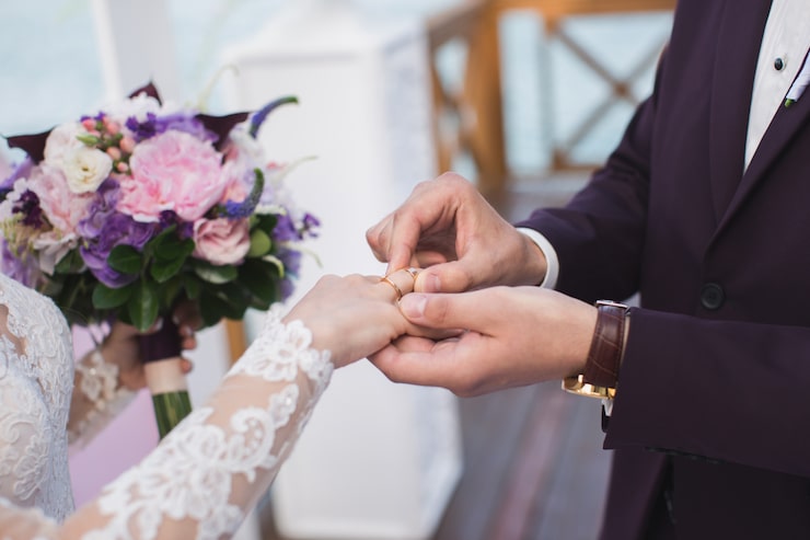 Photo pengantin pria mengenakan cincin pengantin.