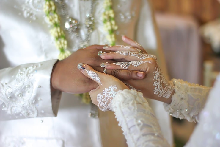 Photo pengantin wanita memasangkan cincin kawin di jari mempelai pria