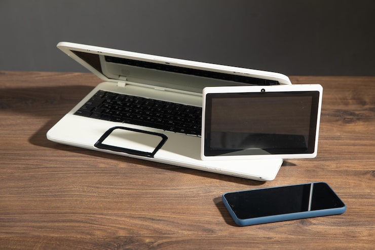 Photo ponsel pintar, tablet, komputer laptop di atas meja kayu