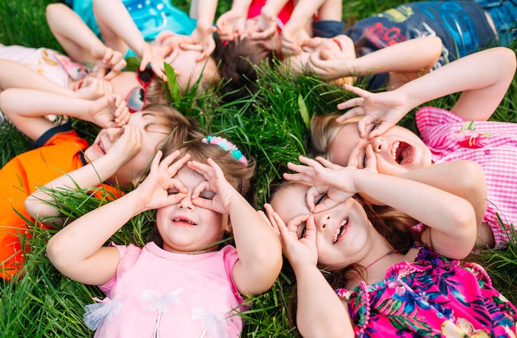 Foto un gruppo di bambini sdraiato sull'erba verde del parco. l'interazione dei bambini.