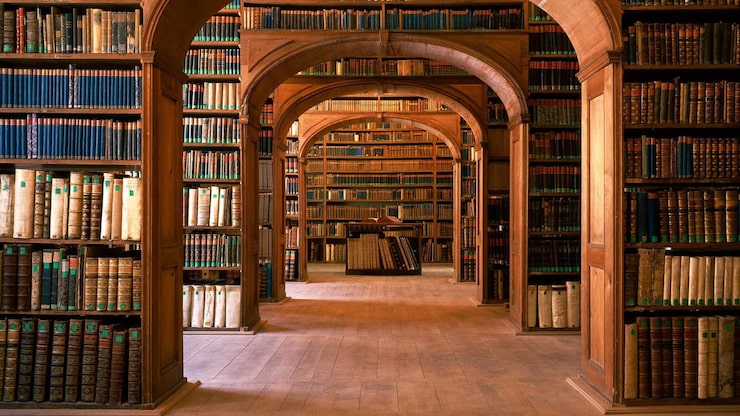 Foto una biblioteca con molti libri sugli scaffali e una persona seduta al centro della stanza