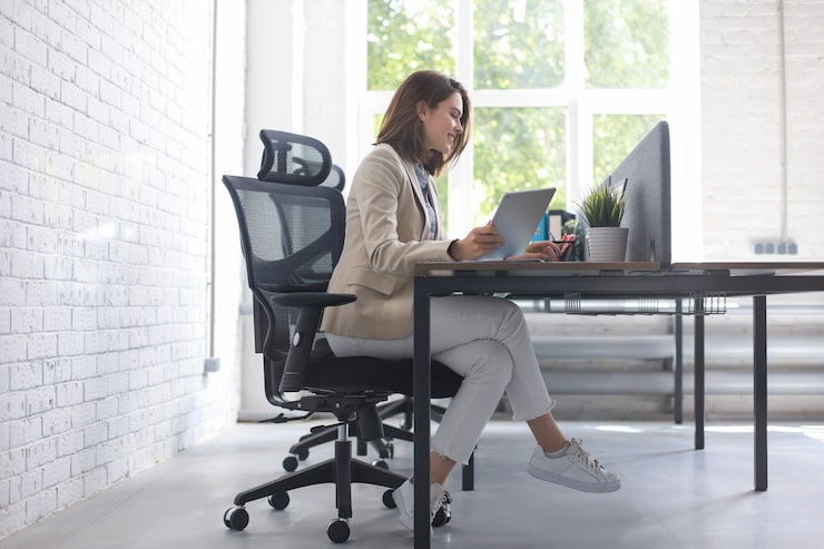 Photo wanita bisnis kaukasia yang cantik sedang bekerja menggunakan tablet digital sambil duduk di kantor kreatif.