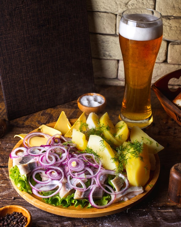 Foto grátis arenque com batatas com cebola, manteiga e verduras, servido com cerveja