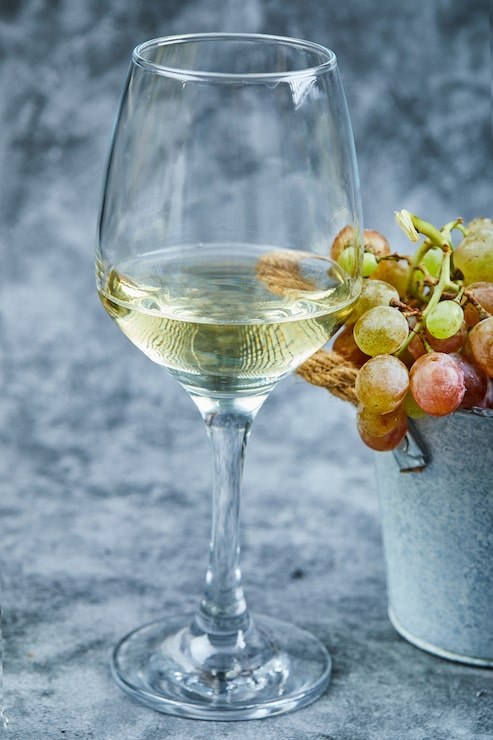 Foto grátis balde de uvas e um copo de vinho na superfície azul.