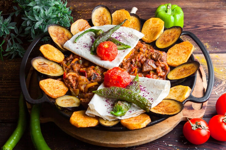 Foto grátis carne de close-up com berinjela, tomate, batata, pão pita cogumelos e pimenta em um prato redondo em uma mesa de madeira escura horizontal