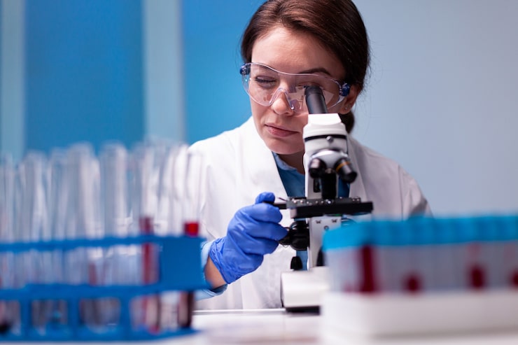 Foto grátis cientista de jaleco branco olhando em um microscópio de última geração para obter experiência em farmácia