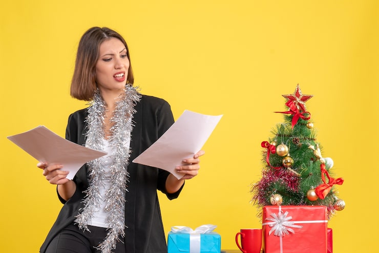 Foto grátis clima de natal com uma bela moça emocional em pé no escritório e segurando documentos em amarelo