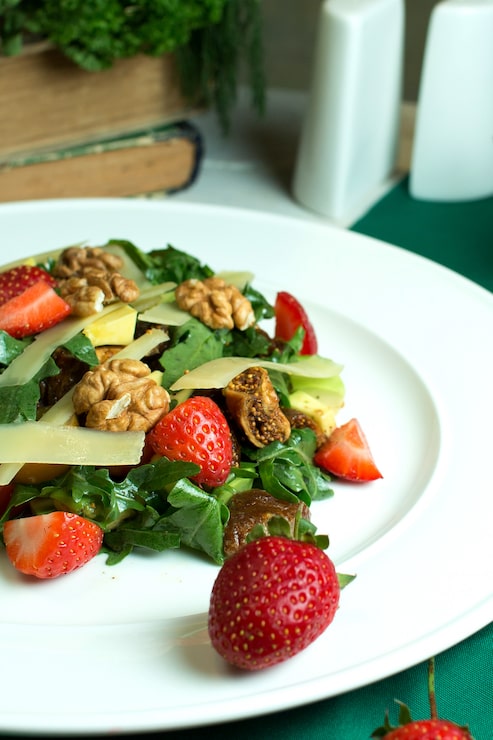 Foto grátis close-up vista de salada fresca com queijo parmesão nozes abacate tomate cereja e morangos em uma tigela branca