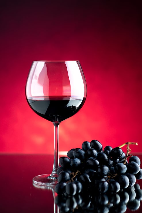 Foto grátis copo de vinho com uvas na vista frontal na parede rosa a