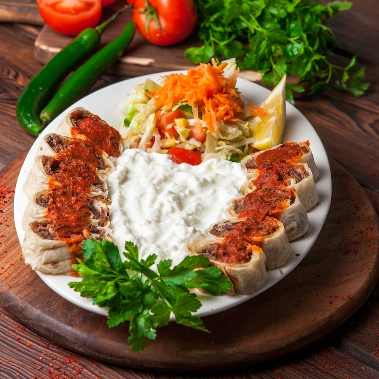Foto grátis de cima beyti kebab com iogurte e limão e salada em prato branco
