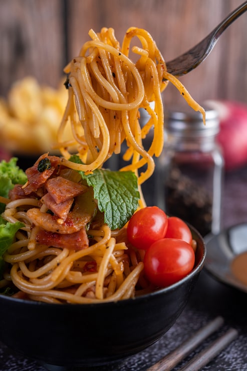 Foto grátis espaguete em um copo preto com tomate e alface.