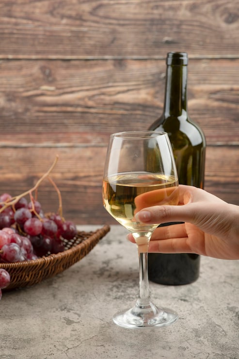 Foto grátis feminino mão segurando um copo de vinho branco na mesa de mármore.