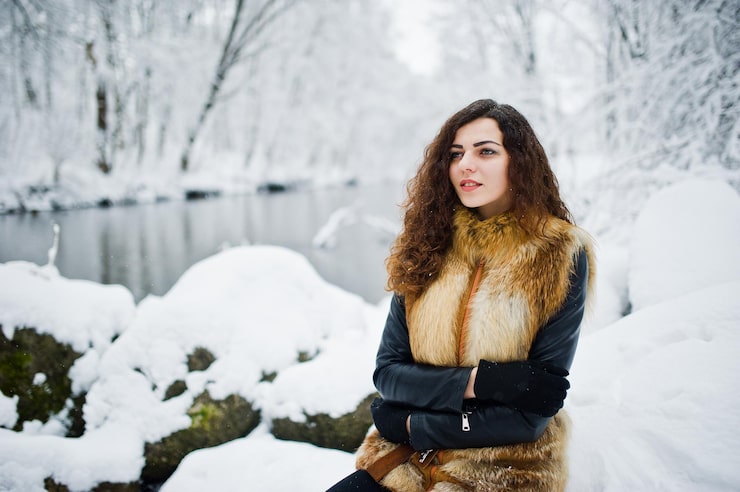 Foto grátis garota encaracolada de elegância com casaco de pele no parque florestal nevado no inverno