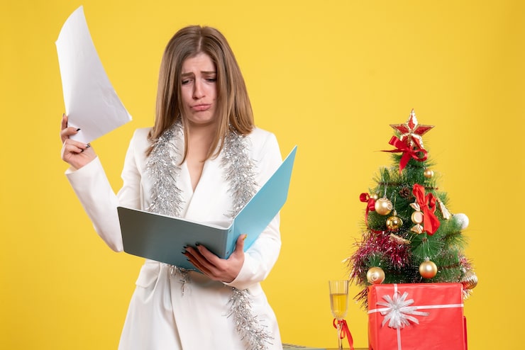 Foto grátis médica de frente, de pé, segurando documentos em fundo amarelo com árvore de natal e caixas de presente