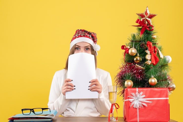Foto grátis médica vista frontal sentada com presentes de natal segurando documentos no fundo amarelo