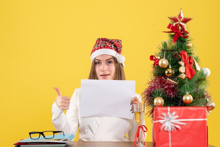Foto grátis médica vista frontal sentada com presentes de natal segurando documentos no fundo amarelo