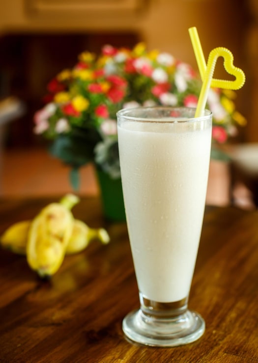 Foto grátis milkshake de banana com fundo de madeira