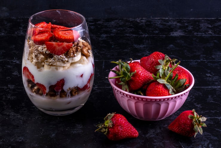 Foto grátis muesli vista frontal com frutas e nozes em um copo com uma tigela rosa com morangos