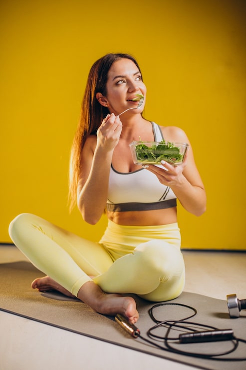 Foto grátis mulher comendo salada isolada em fundo amarelo