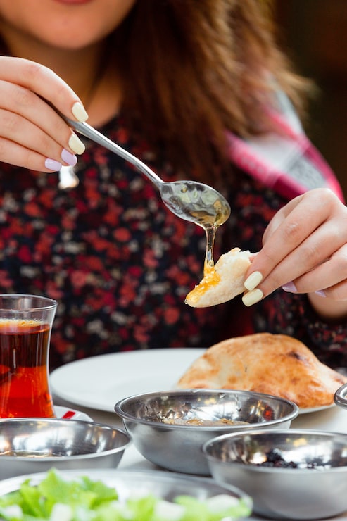 Foto grátis mulher tomar café da manhã com pão e mel