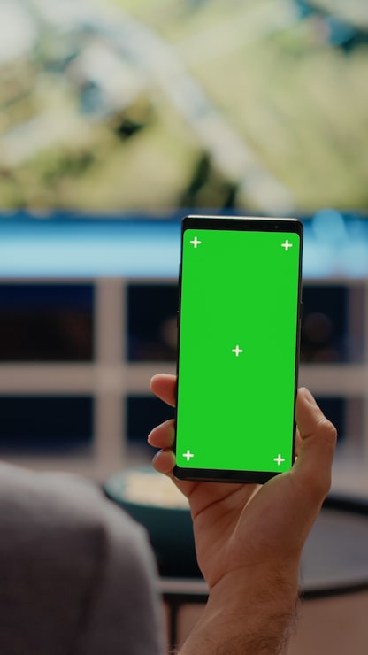 Foto grátis pessoa segurando um telefone celular com tela verde verticalmente