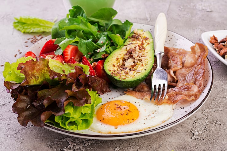 Foto grátis prato com um alimento de dieta ceto. ovo frito, bacon, abacate, rúcula e morangos. keto café da manhã.