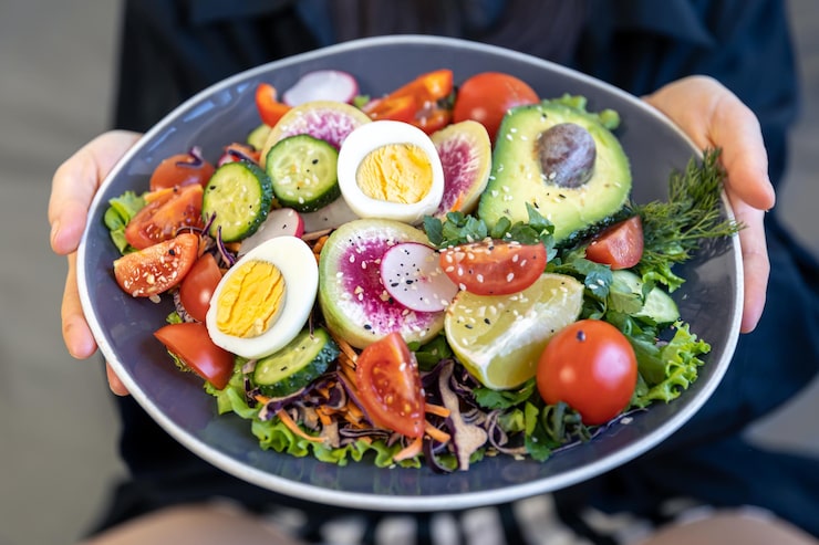 Foto grátis salada apetitosa com legumes frescos e ovos num prato em mãos femininas