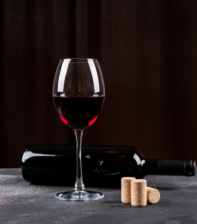 Foto grátis vista lateral de vinho vermelho em vertical preto